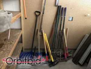 Lot of assorted snow shovels, pickaxes, post hole diggers, and other assorted lawn tools,...